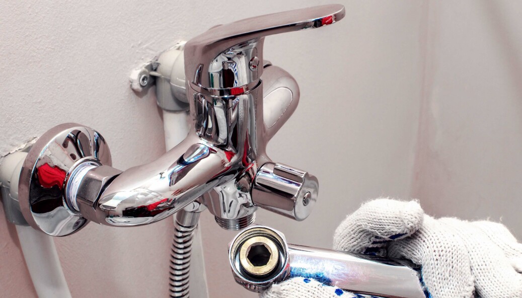 Installing faucet. Plumber fixing water tap. Men's hands in gloves are fixing bath tap into place. Installing faucet. Plumber fixing water tap. Men's hands in gloves are fixing bath tap into place.